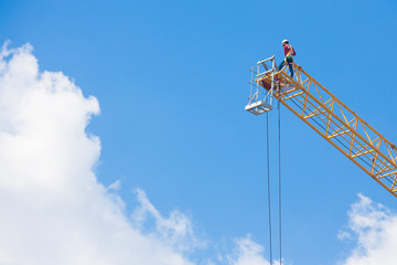 Workers on a large construction crane on blue sky