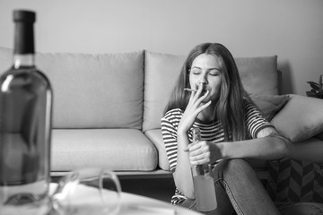 Wall Mural - Young woman with addiction to alcohol and cigarettes relaxing at home