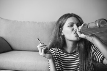 Wall Mural - Young woman with addiction to alcohol and cigarettes relaxing at home