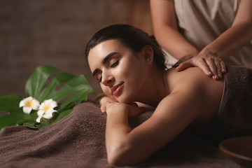 Beautiful young woman receiving massage in spa salon