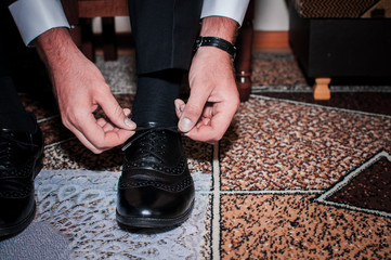 White man puts black shoes on the white background