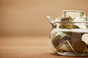 Wall Mural - close up view of glass jar with dollar banknotes and metal coins