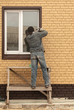 © schankz - The worker installs a metal window in the house