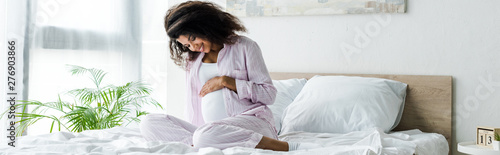 Fotografía panoramic shot of attractive pregnant african american woman looking at belly an