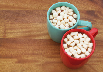 Two cups with cocoa drink and marshmallows on wooden table with copyspace