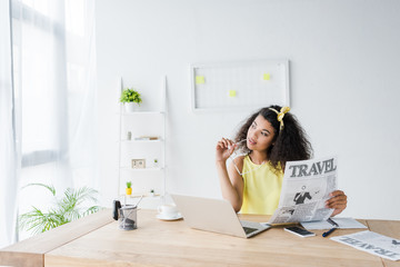 Wall Mural - pensive african american woman holding travel newspaper and glasses