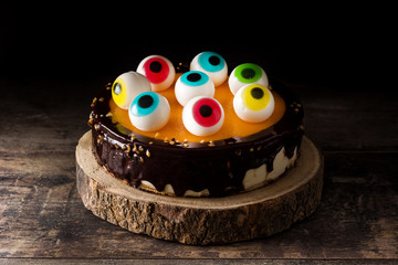 Halloween cake with candy eyes decoration on wooden table and black background