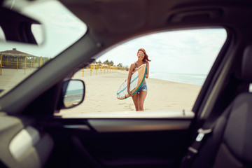 Wall Mural - Surfer woman with sexy body in bikini with surf board walking on sea beach..