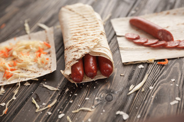 Wall Mural - spicy sausages in pita bread on a wooden table