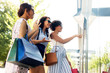 © Syda Productions - sale, consumerism and people concept - happy young women with shopping bags pointing finger to shop window in summer city