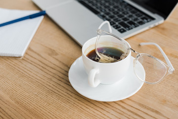 Wall Mural - selective focus of saucer and cup of coffee near laptop