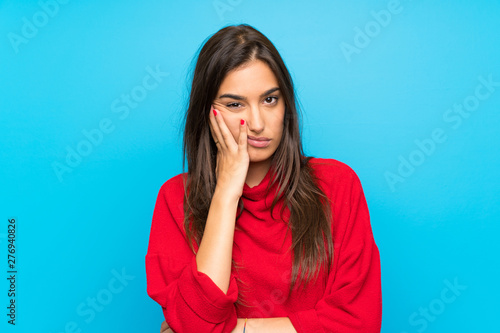 Cuadros en Lienzo Young woman with red sweater over isolated blue background unhappy and frustrate