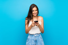 Young Woman Over Isolated Blue Background Sending A Message With The Mobile