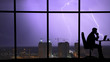© realstock1 - The man working at the table near a window on a city lightning background