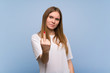 © luismolinero - Young woman over blue wall making horn gesture
