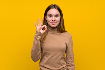 Young woman over colorful background showing an ok sign with fingers