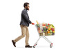 Bearded guy walking and pushing a shopping cart with food products