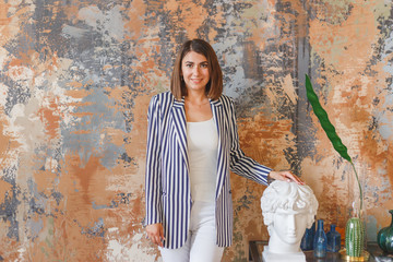 Young business woman in striped jacket standing beside art object.