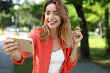 Sticker - Happy young woman taking selfie in park