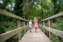 Brother And Sister Crossing Small Wooden Bridge