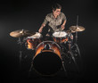 © puhimec - Professional drummer playing on drum set on stage on the black background