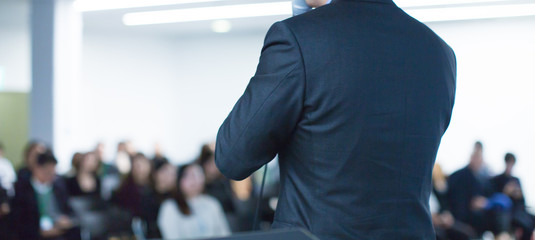 Fototapete - Speaker at conference giving a talk about corporate business. Audience in hall with presenter giving presentation. Seminar lecture with corporate executive giving speech during business workshop.