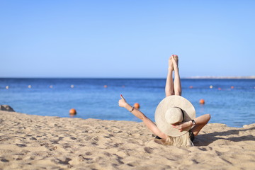 Young pretty hot sexy woman relaxing in swimsuit on stones with blue sea and sky on background. Summer Vacation Concept. Back View