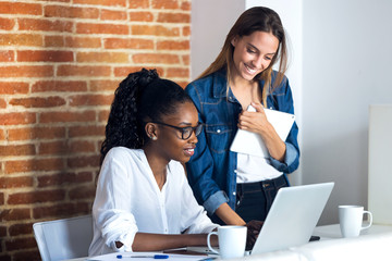 Canvas Print - Two pretty young business women working together with digital tablet and laptop in the office.