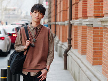Portrait Of A Handsome Chinese Young Man With Korean Style Clothes Walking And Looking At Camera With Sad Expression Against Shanghai Street Background, Male Fashion, Cool Asian Young Man Lifestyle.