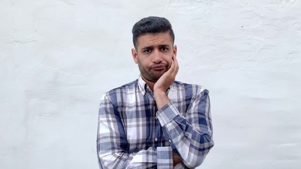 Wall Mural - Portrait of query handsome bearded man in blue checkered shirt standing touching his face and thinking what to do or try to find answer or idea. indoor studio shot isolated on white wall background.