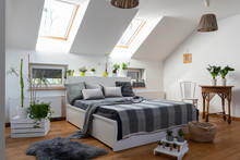 White Bedroom With Double Bed, Grey Pillows And Green Plants In Scandinavian Style In The Attic.