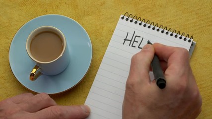 Canvas Print - hello august - a man hand writing a note with a black marker in a notebook, overhead view with a cup