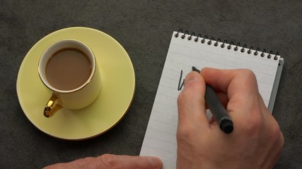 Canvas Print - way to go - a man hand writing a note with a black marker in a notebook, overhead view with a cup of