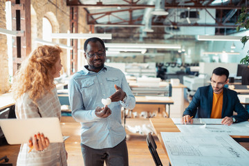 Canvas Print - Dark-skinned leader of design project speaking to his assistant