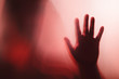 © charnsitr - Shadow of the ghost hand behind frosted glass for horror concept