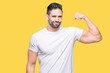 © Krakenimages.com - Handsome man wearing white t-shirt over yellow isolated background Strong person showing arm muscle, confident and proud of power
