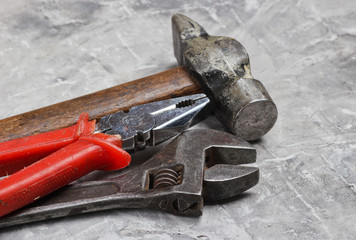 Wall Mural - Old work tool on gray concrete background. Pliers, wrench, hammer