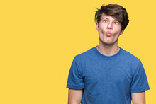 Young Handsome Man Wearing Blue T-shirt Over Isolated Background Making Fish Face With Lips, Crazy And Comical Gesture. Funny Expression.