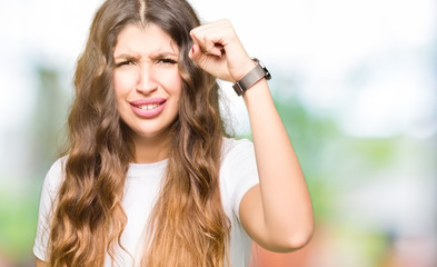 Poster - Young beautiful woman wearing casual white t-shirt angry and mad raising fist frustrated and furious while shouting with anger. Rage and aggressive concept.