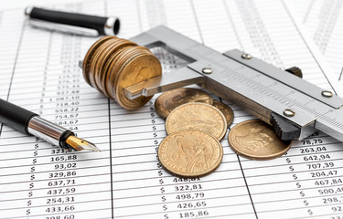 Vernier caliper with coins on documents with financial data. Business and financial concept.