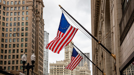 Wall Mural - American flag in Chicago, Illinois downtown. Highrise buildings and cloudy sky background.