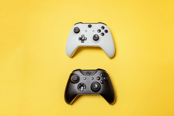 White and black two joystick gamepad, game console on yellow colourful trendy modern fashion pin-up background. Computer gaming competition videogame control confrontation concept. Cyberspace symbol