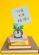 © Zofia - Handwriting text writing Time For Review. Conceptual photo review of a system or situation in its formal examination Alarm clock note stacked notepads old books colored background