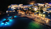 Aerial Drone Night Shot Of Famous Psarou Beach With Luxury Resorts And Yachts Docked, Mykonos Island, Cyclades, Greece