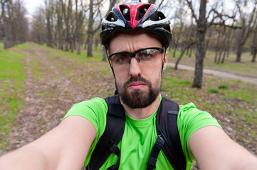 Sad guy in sportswear and helmet taking selfie on nature