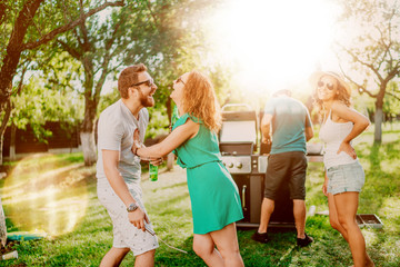 Group of multi-ethnic friends having beers and cooking on garden barbecue. Lifestyle, leisure concept