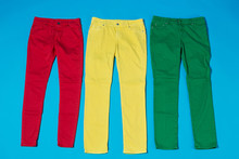 Three Colored Pants On A Blue Background, The Concept Of A Joyful Life And Shopping