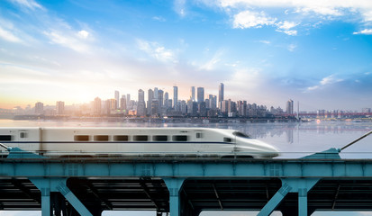 Wall Mural - High-speed rail speeds on Bridges and the modern city skyline of chongqing, China