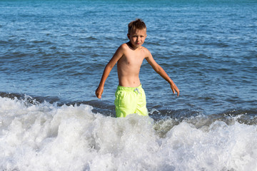 Wall Mural - child is swimming in the sea, a little boy is frozen