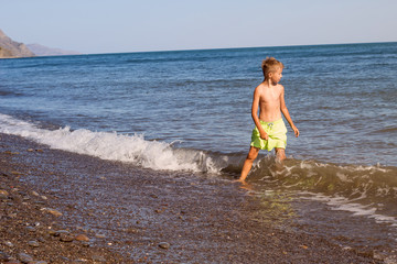 Wall Mural - child swimming in the sea, a little boy running along the coast